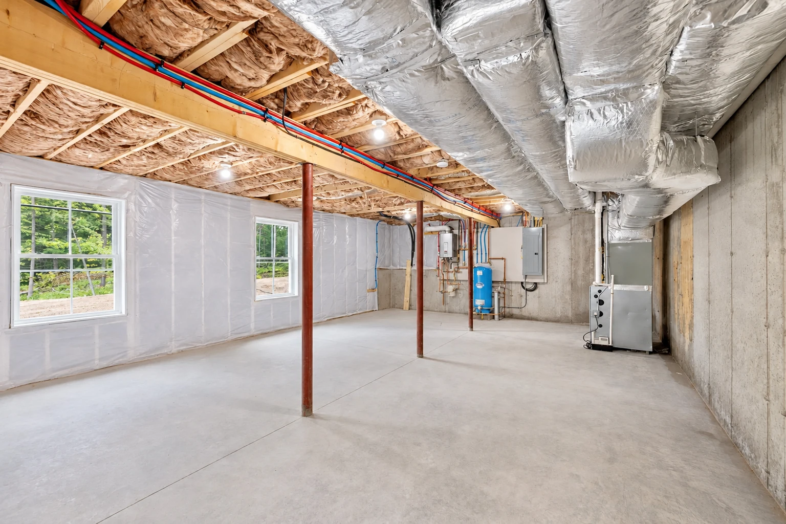 Unfinished basement with insulation between ceiling joists, silver ductwork overhead, and plastic sheeting on one wall.